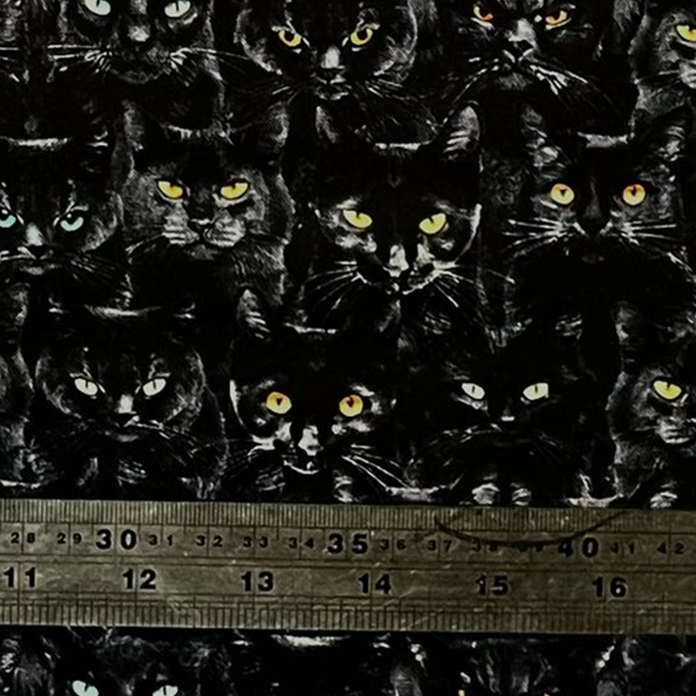 100% cotton fabric with rows of black cats all with different coloured staring eyes