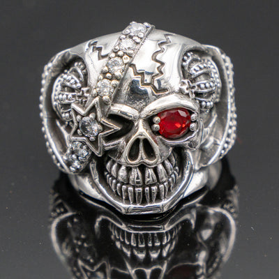 Pirate Skull Ring with an eye patch studded with cubic zirconia stones the good eye is a red cubic zirconia.  On both sides of the skull is a crown, he's got a great sinister grin!