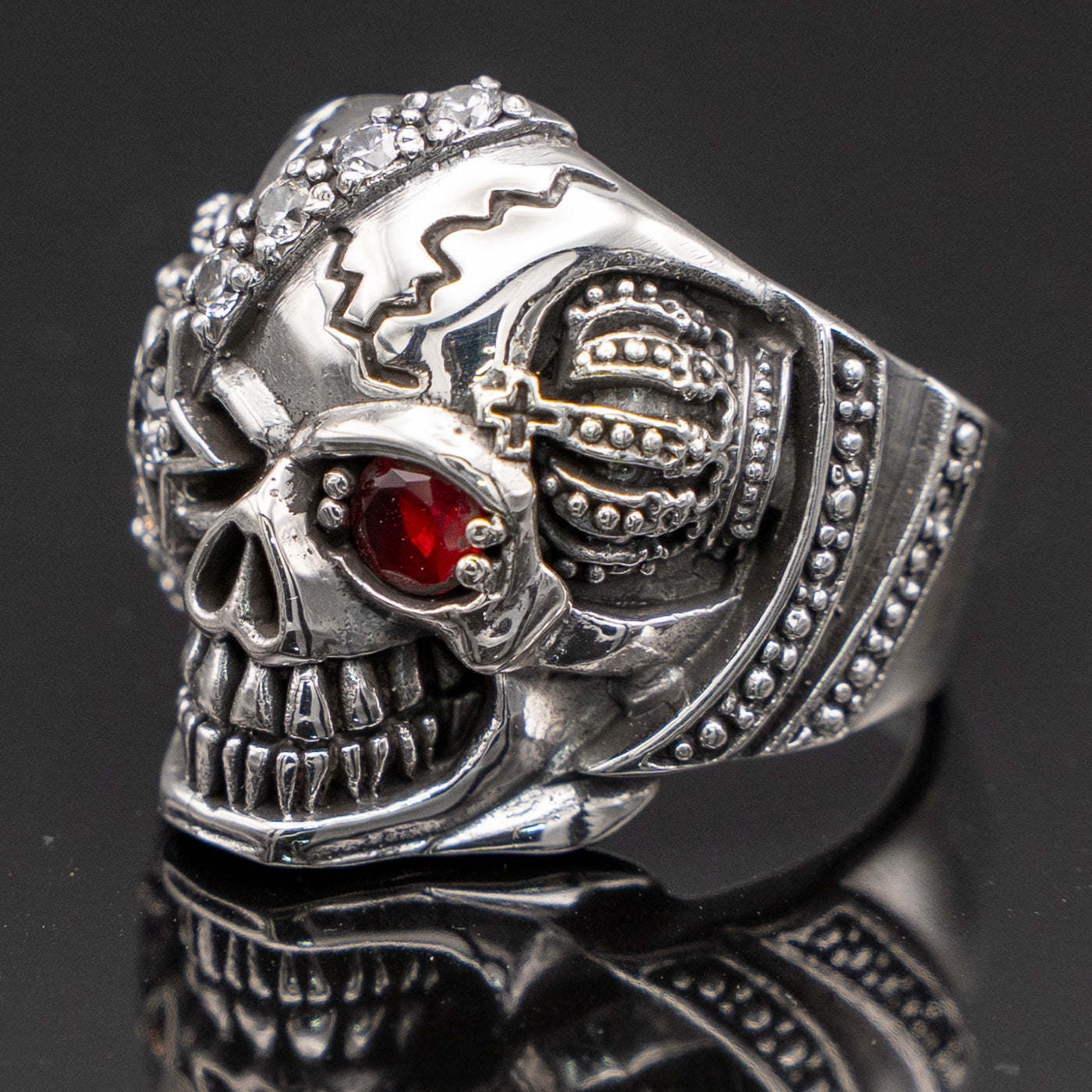 Pirate Skull Ring with an eye patch studded with cubic zirconia stones the good eye is a red cubic zirconia.  On both sides of the skull is a crown, he's got a great sinister grin!