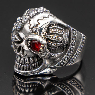 Pirate Skull Ring with an eye patch studded with cubic zirconia stones the good eye is a red cubic zirconia.  On both sides of the skull is a crown, he's got a great sinister grin!