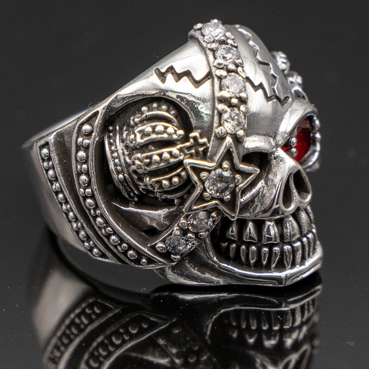 Pirate Skull Ring with an eye patch studded with cubic zirconia stones the good eye is a red cubic zirconia.  On both sides of the skull is a crown, he's got a great sinister grin!
