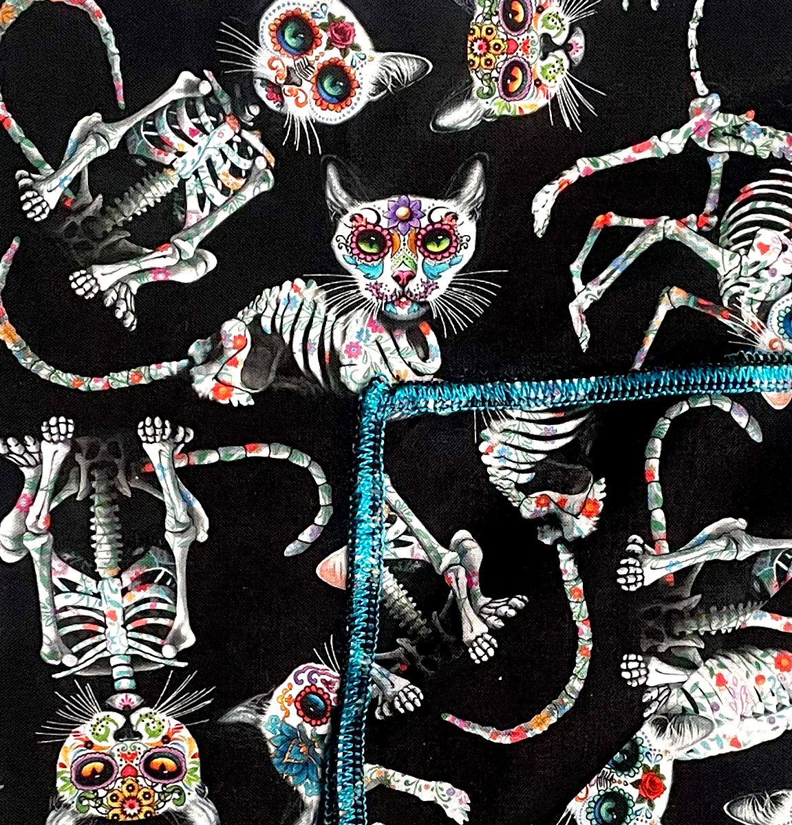 Handmade bandana, with skeleton cats decorated in day of the dead designs on black fabric.  You can wear our bandana as a thin band or wrap it to cover your entire head, great for sun cover.  You can even wear it as a neckerchief or wrist wrap.  It is approx. 21.5" x 21.5" 100% machine washable cotton from Timeless Treasures