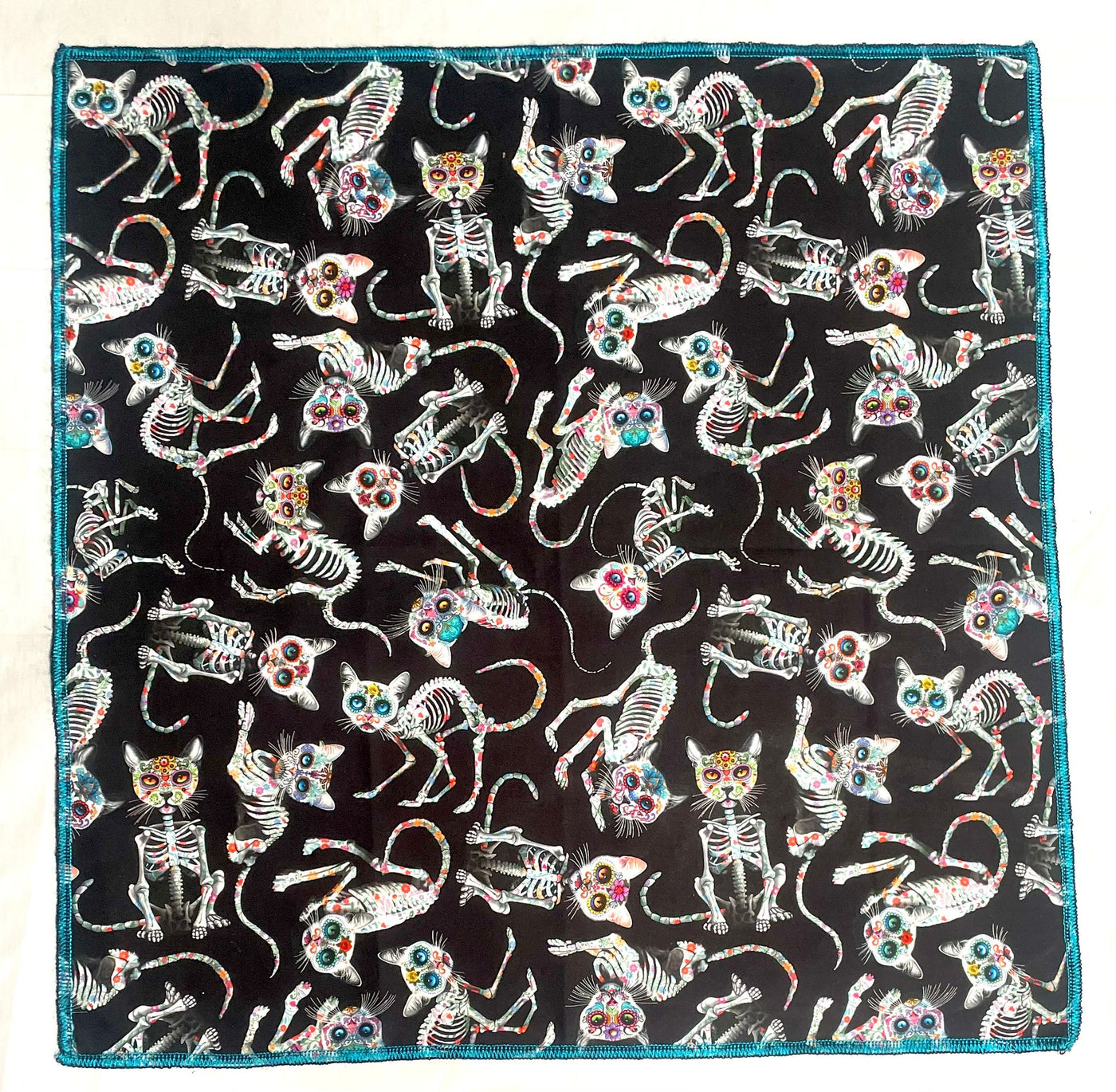 Handmade bandana, with skeleton cats decorated in day of the dead designs on black fabric.  You can wear our bandana as a thin band or wrap it to cover your entire head, great for sun cover.  You can even wear it as a neckerchief or wrist wrap.  It is approx. 21.5" x 21.5" 100% machine washable cotton from Timeless Treasures
