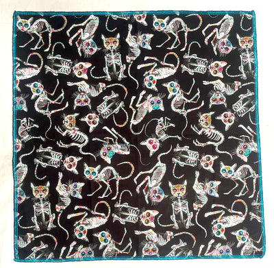 Handmade bandana, with skeleton cats decorated in day of the dead designs on black fabric.  You can wear our bandana as a thin band or wrap it to cover your entire head, great for sun cover.  You can even wear it as a neckerchief or wrist wrap.  It is approx. 21.5" x 21.5" 100% machine washable cotton from Timeless Treasures
