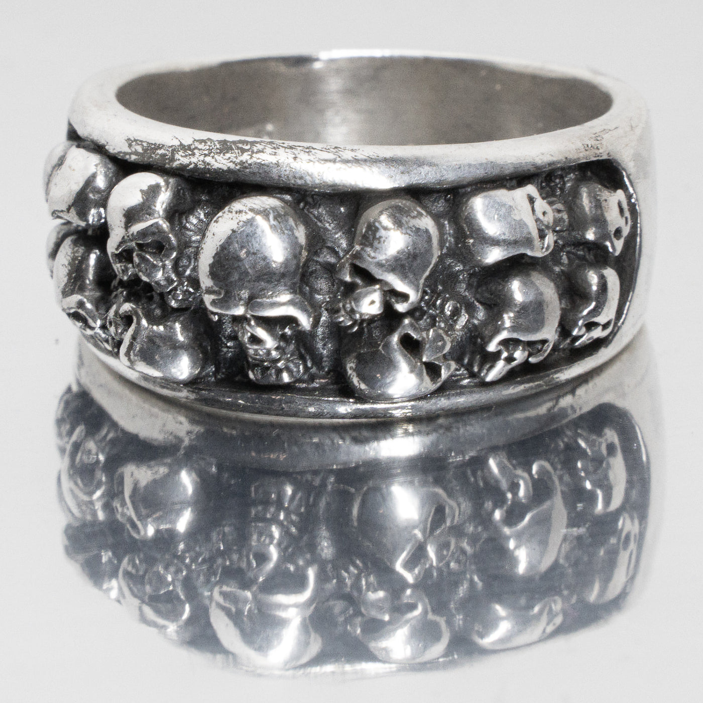 Cluster of 13 skulls on a 925 sterling silver ring band.  Out of the 13 there is 1 large skull in the centre with 3 rows of 2 skulls on either side
